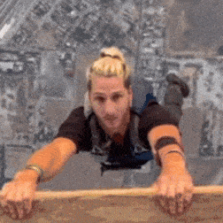 a man in a black shirt is laying on a wooden plank