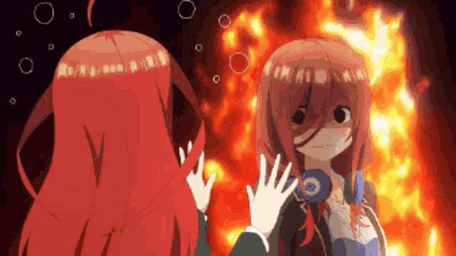 a girl with red hair is standing in front of a fire and talking to another girl .