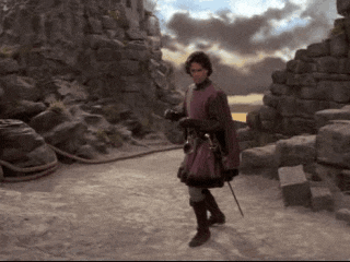 a man in a purple cape is walking down a dirt path