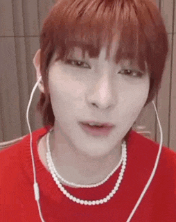 a close up of a person wearing a pearl necklace and ear buds .
