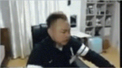 a blurry picture of a man sitting at a desk in a living room .