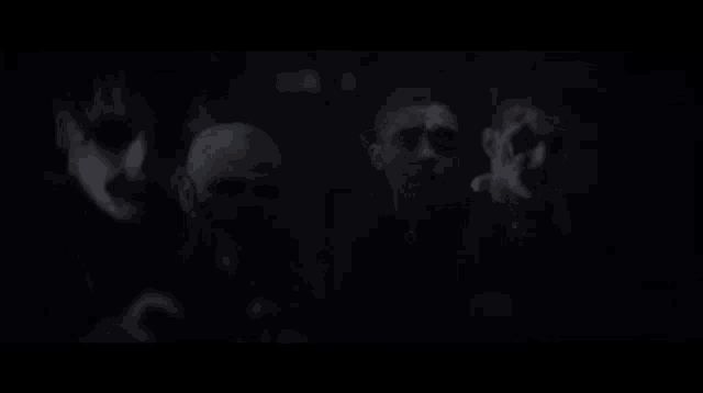 a group of people are standing in the dark with their faces painted .