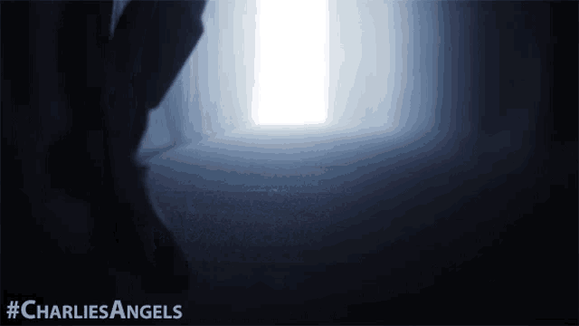 a poster for charlie 's angels shows a person standing in a dark room