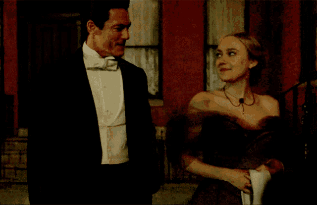 a man in a tuxedo stands next to a woman in a fur stole
