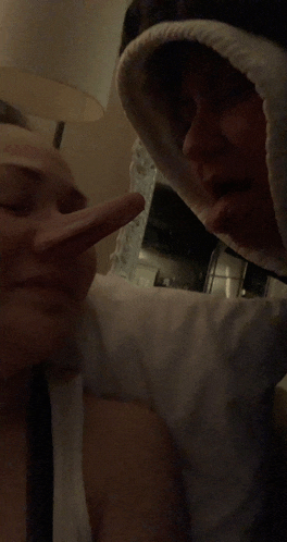 a woman with a long nose looks at a man with a hood on