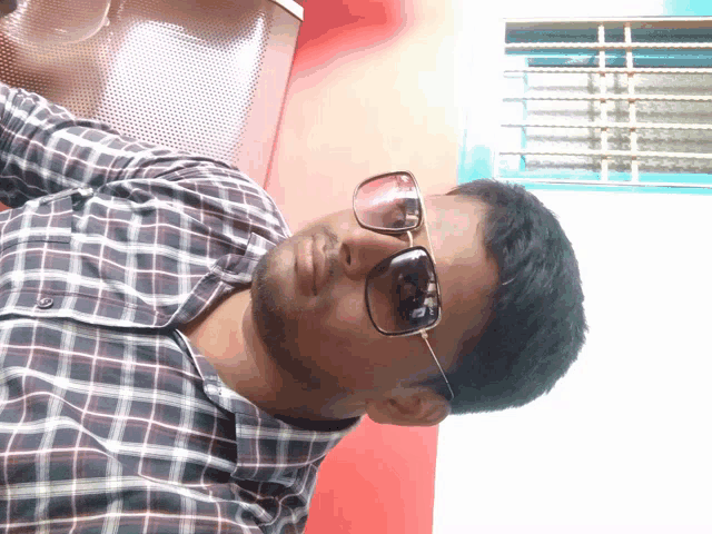a man wearing sunglasses and a plaid shirt takes a selfie