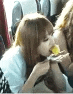 a woman is eating a piece of food while sitting in a bus .