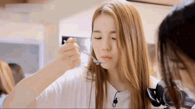 a woman with long blonde hair is eating with a spoon ..