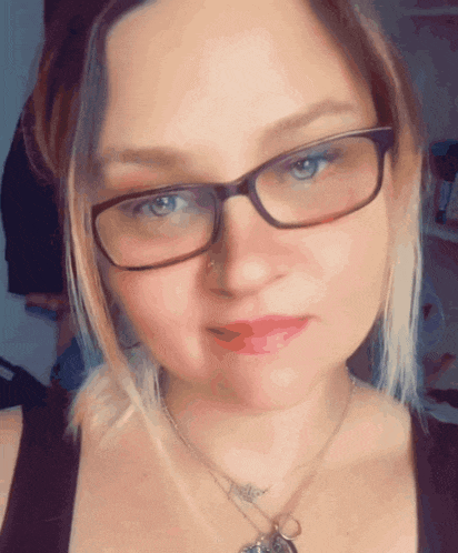 a close up of a woman wearing glasses and a necklace with a pendant that says " i love you "