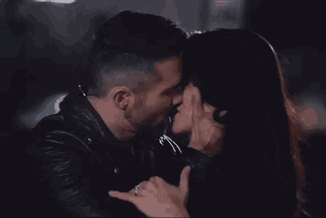 a man and a woman are kissing in a dark room at night .