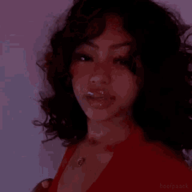 a girl with curly hair is wearing a red shirt and necklace .