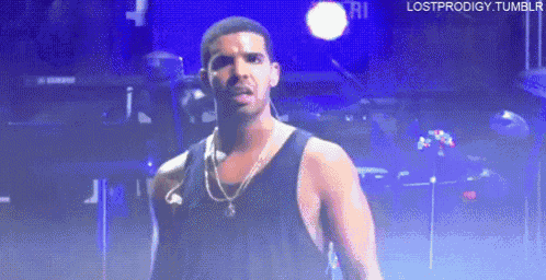 a man wearing a black tank top and a necklace is standing on stage .