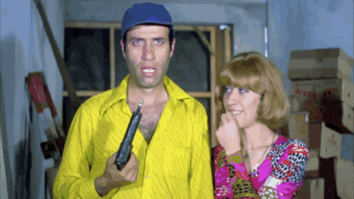 a man in a yellow shirt holding a gun next to a woman