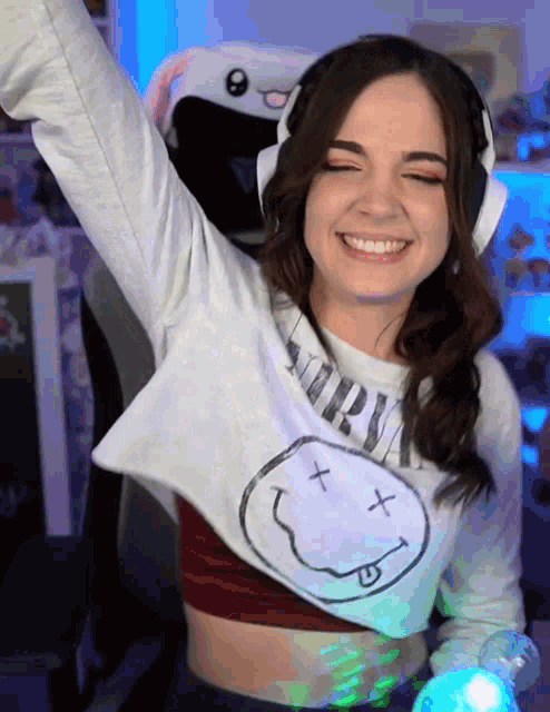a woman wearing a nirvana shirt and headphones is smiling