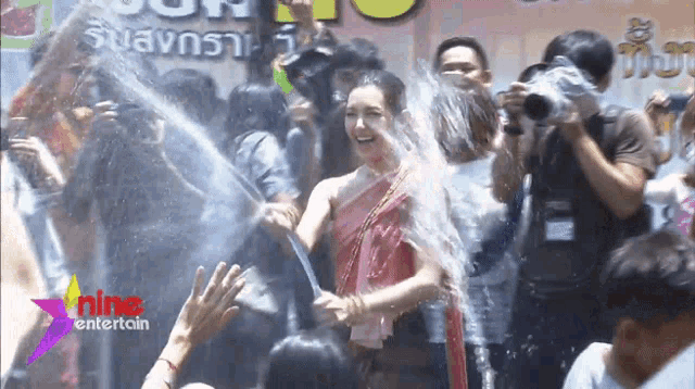 a woman in a red dress is being sprayed with water in front of a sign that says sunshine entertain