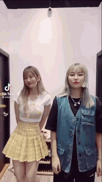 two young women are standing next to each other in a room .