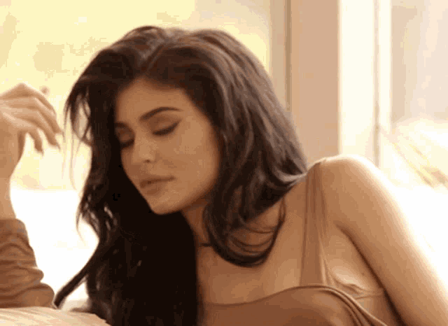 a woman with long black hair is laying on a bed
