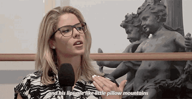 a woman wearing glasses is talking into a microphone and says his lips are like little pillow mountains
