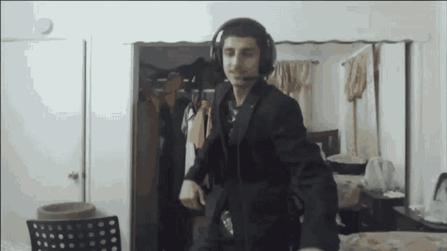 a man in a suit and headphones is dancing in a room