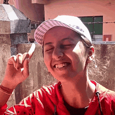 a girl wearing a red jacket and a white hat is smiling