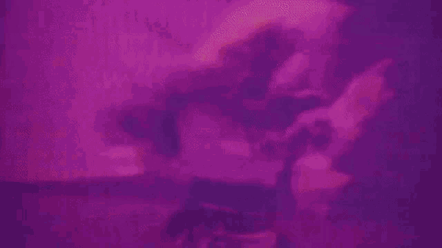 a woman is dancing in front of a purple background in a room .