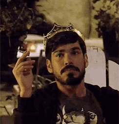 a man with a beard and a crown on his head smoking a cigarette