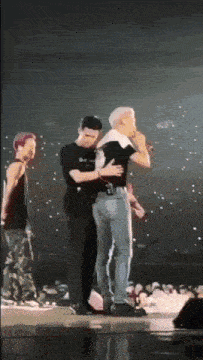 a man is hugging another man on a stage while a crowd watches .