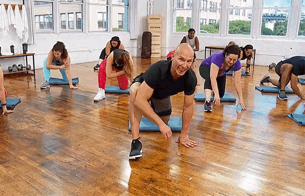 a group of people are doing stretching exercises in a gym and one of them is smiling