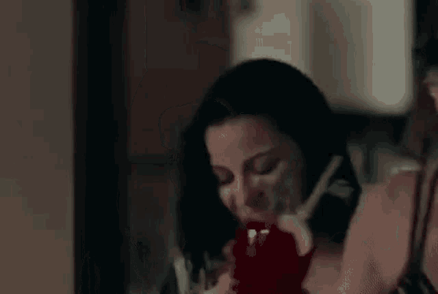 a woman is holding a red apple in her hand while talking on a phone .