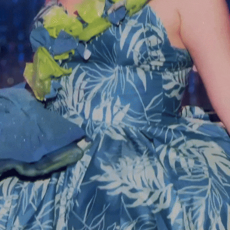 a woman in a blue and white floral dress is holding a snake