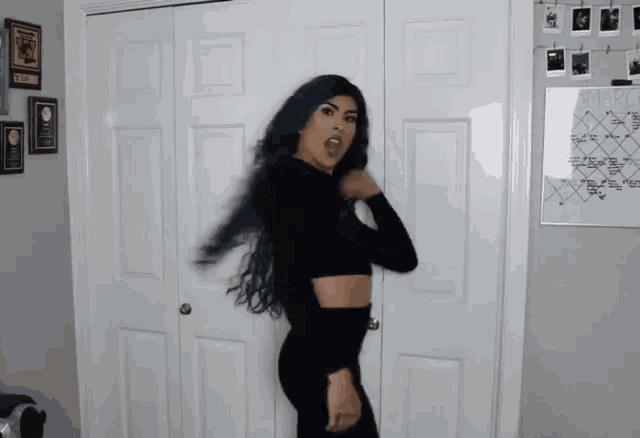 a woman with blue hair is standing in front of a white door with a calendar on it that says april