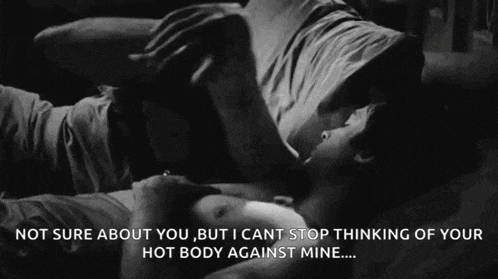 a man and woman are laying on a bed and kissing .