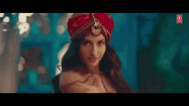 a woman wearing a red turban and a nose ring is looking at the camera .