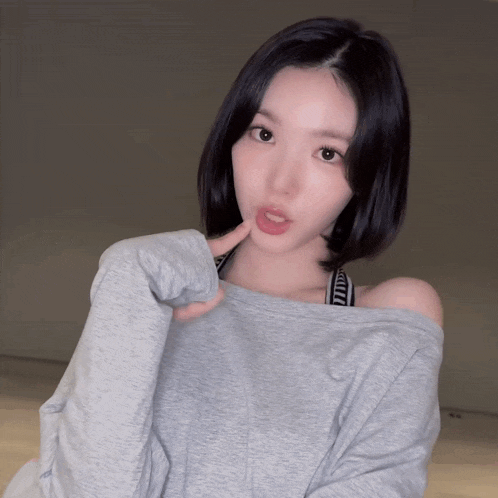 a woman wearing a grey off the shoulder sweatshirt and a black and white bra