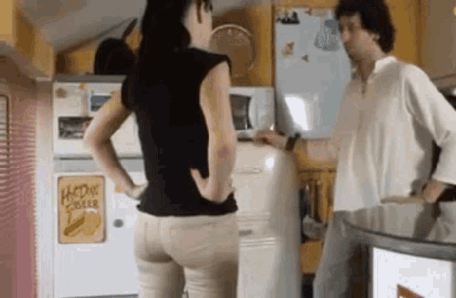 a man and a woman are standing next to each other in a kitchen in front of a refrigerator .