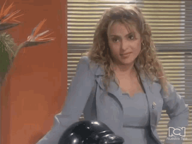 a woman in a blue suit stands next to a black helmet