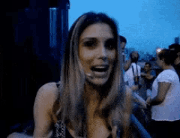 a woman with her mouth open is standing in a crowd of people