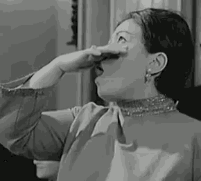 a black and white photo of a woman holding her nose .