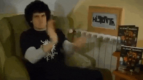 a man in a black shirt is sitting in a chair in front of a radiator and a sign that says hispania .