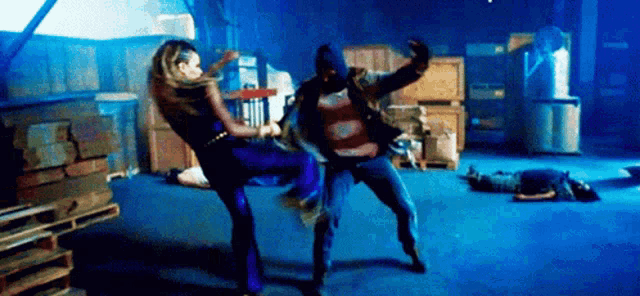 a man and a woman are fighting in a dark room in a warehouse .