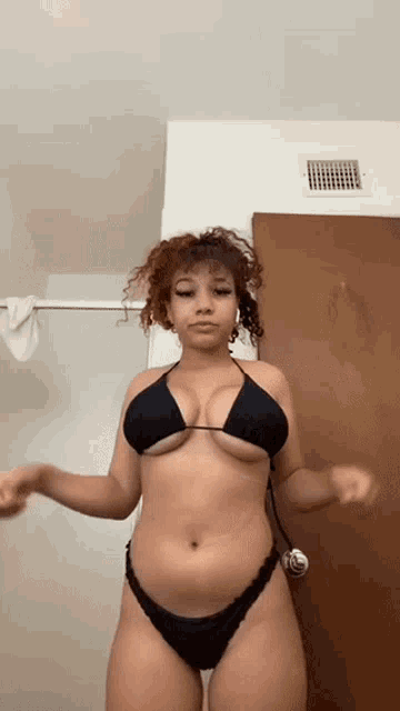 a woman in a bikini is standing in front of a door in a bathroom .