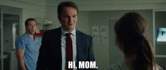 a man in a suit and tie is talking to a woman and says hi mom .