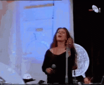 a woman singing into a microphone in front of a projector screen