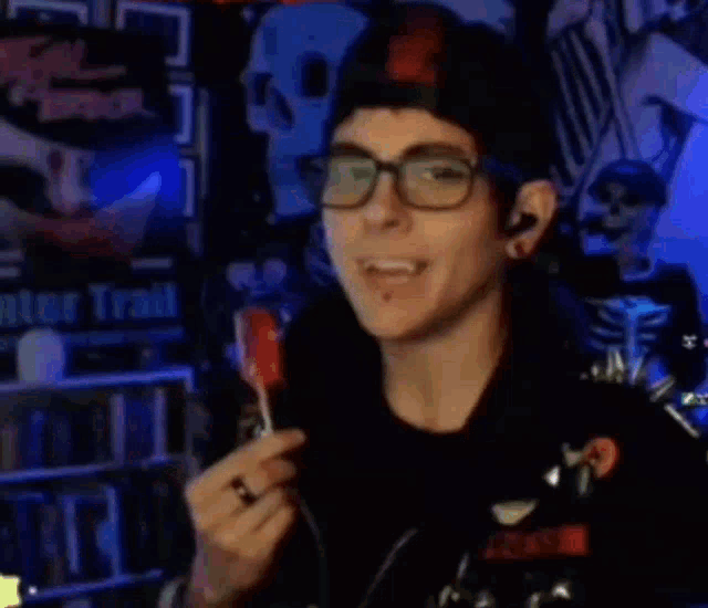 a man wearing glasses and a hat is eating a lollipop