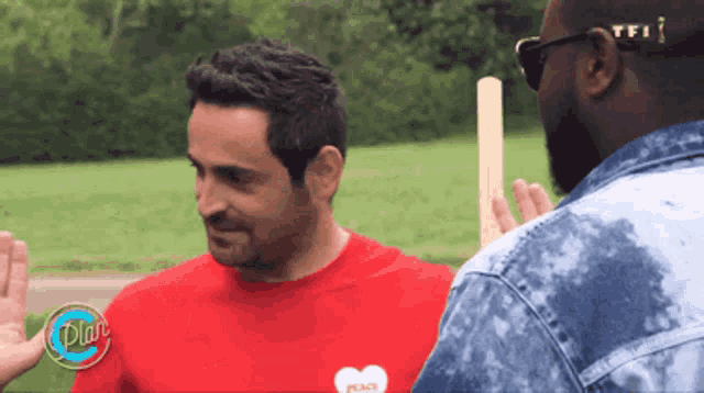 a man wearing a red shirt that says peace is talking to another man