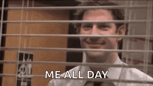 a man is smiling while looking out of a window with blinds and says `` me all day '' .