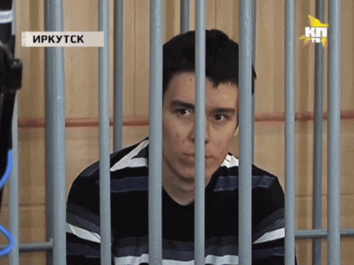 a man in a striped shirt is behind bars with a sign that says " irkutsk " on it