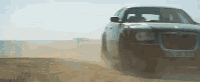 a car is driving down a dirt road with dust coming out of it .