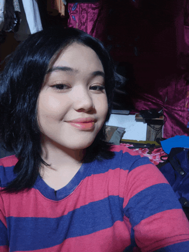 a girl wearing a red and blue striped shirt is smiling