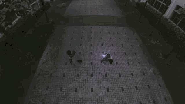 a group of people are walking down a brick sidewalk at night with their lights on .
